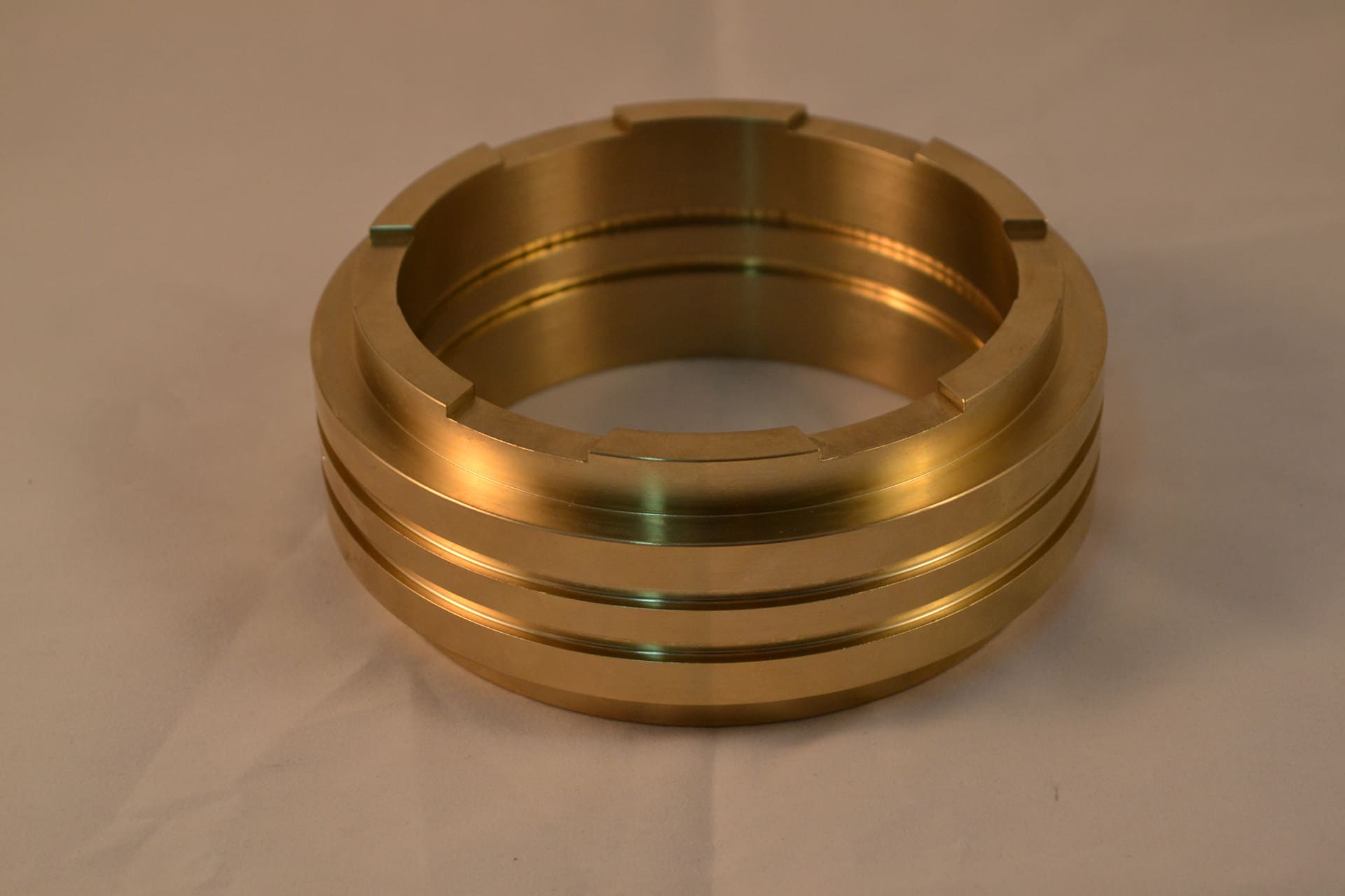 Precision CNC machined brass ring featuring external O-ring grooves and top alignment notches.