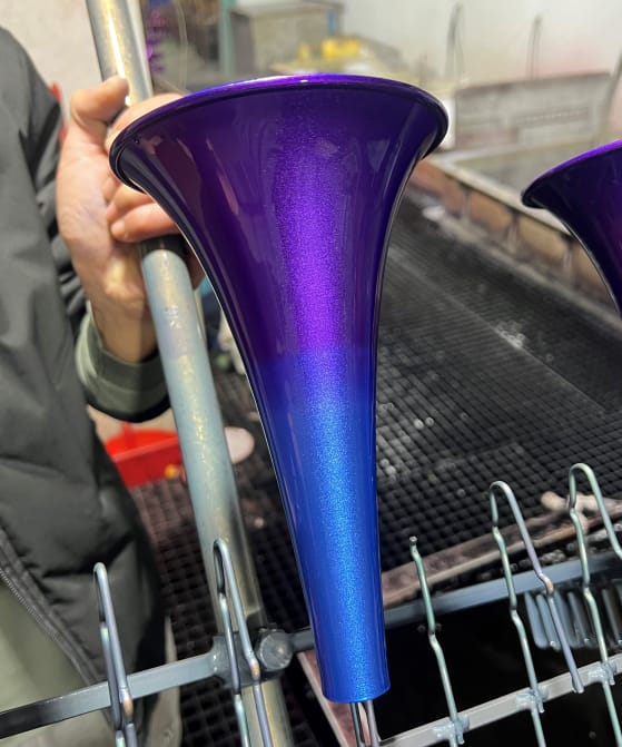 Custom spray painting application showing a high-gloss purple to metallic blue gradient finish on funnel-shaped parts.
