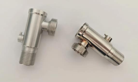 Two stainless steel fluid control housings showing machined threads, side ports, and weld traces.