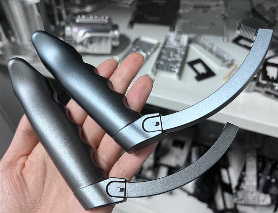 Two CNC machined aluminum handles with gunmetal grey anodized finish and bead blasted texture for ergonomic handheld device.