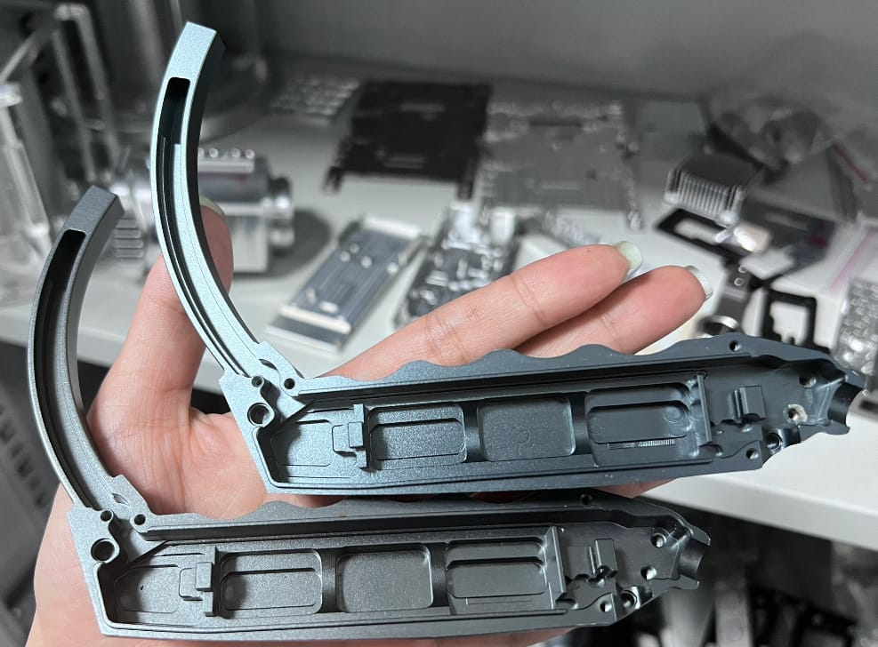 holding two halves of a CNC machined aluminum split-housing handle with thin walls and grey anodized finish.